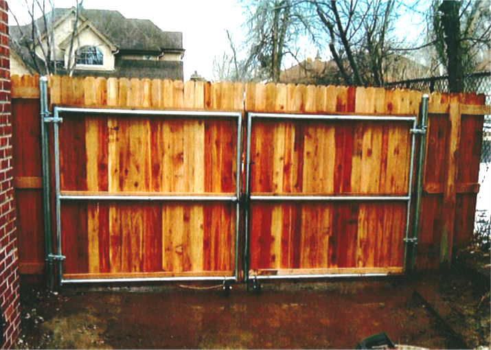 Wooden double gate with metal frame, part of a wooden fence, in front of a house.
