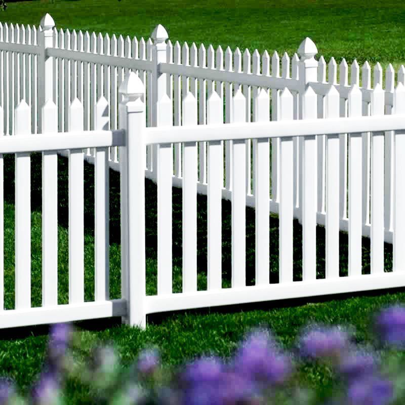 White picket fence on a grassy lawn, with a hint of purple flowers in the foreground.