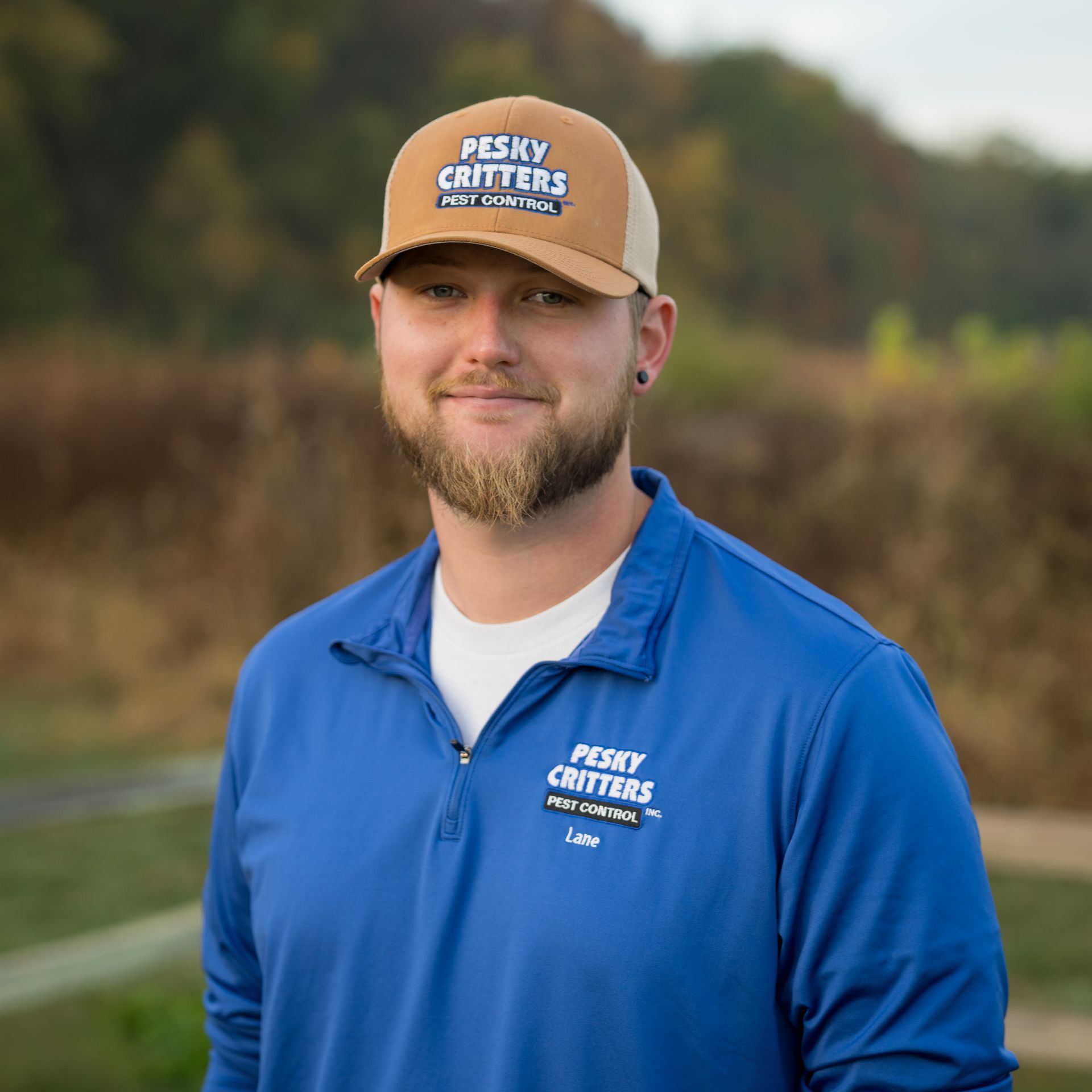 A person with a beard wearing a tan cap and blue pullover with 