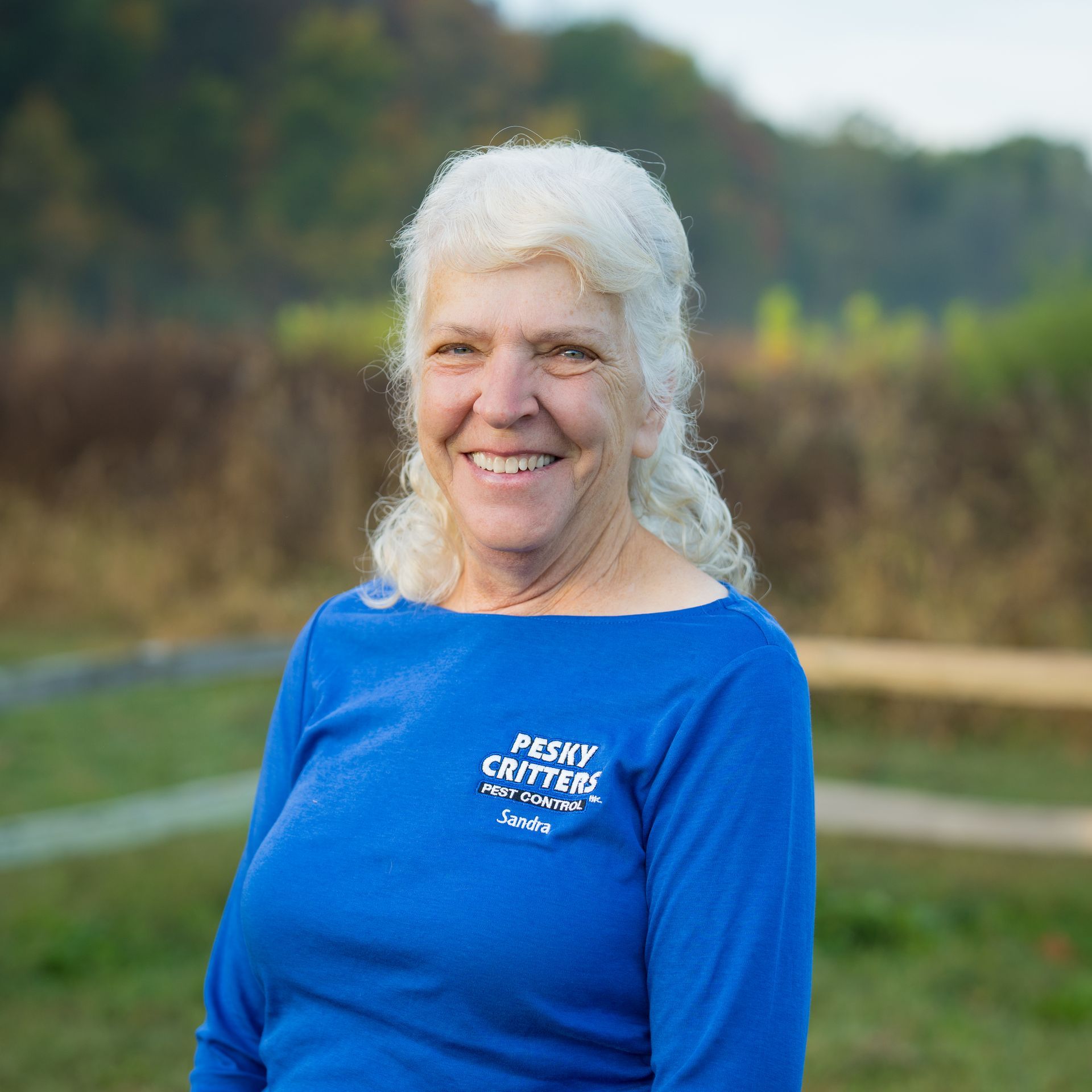 A smiling person wearing a blue 