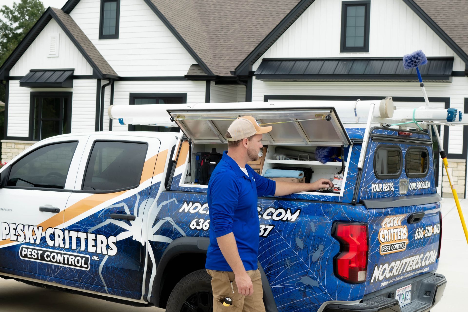 A worker in a blue shirt reaches into an open service truck compartment labeled 