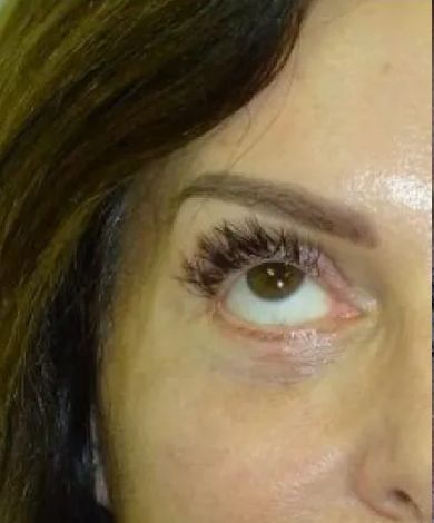 Close-up of a person's eye, showcasing dark eyelashes, light brown eyebrows, and light skin.