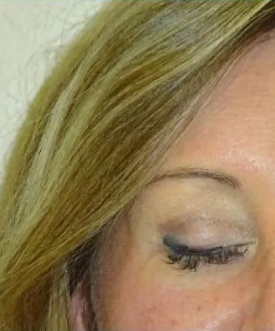 Woman with blonde hair, closed eye, visible eye makeup, and light skin.