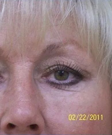 Close-up of a person's eye with eye makeup, dated 02/22/2011. The eye is surrounded by light skin.