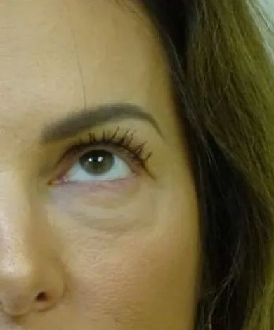 Close-up of a person's eye, looking upwards. Visible are an eyebrow, eyelashes with mascara, and slight under-eye shadows.