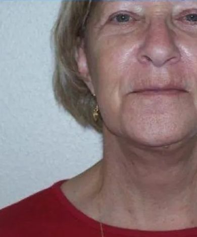 Woman with fair skin and short hair, wearing a red shirt, looking at the camera.