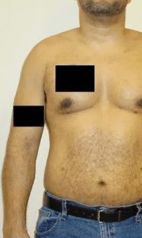 Man's torso and arm with black rectangles obscuring portions. He wears jeans and a belt, standing against a wall.