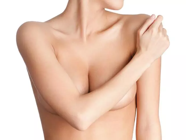 Woman touching right shoulder, nude torso visible.