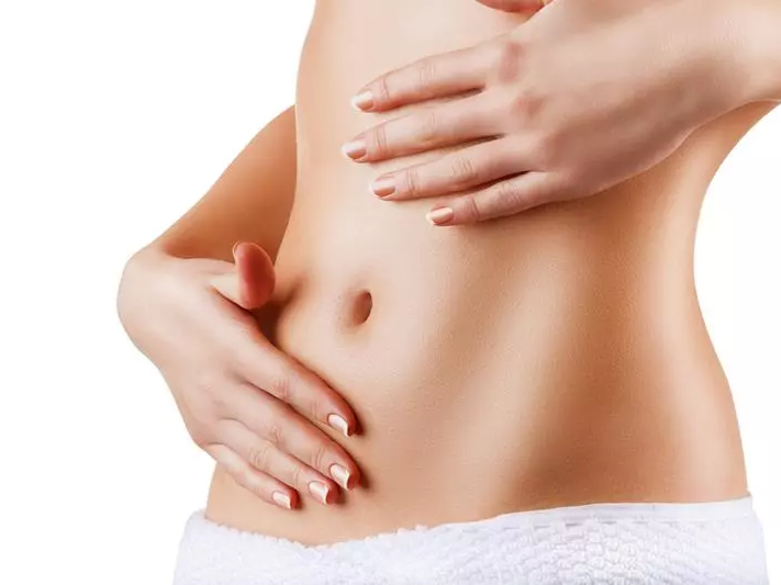 Person's hands gently touching abdomen, white towel visible.