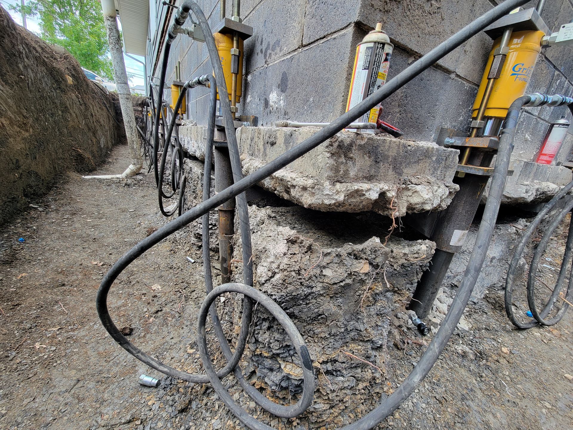 Foundation repair with hydraulic jacks, soil, and concrete blocks.