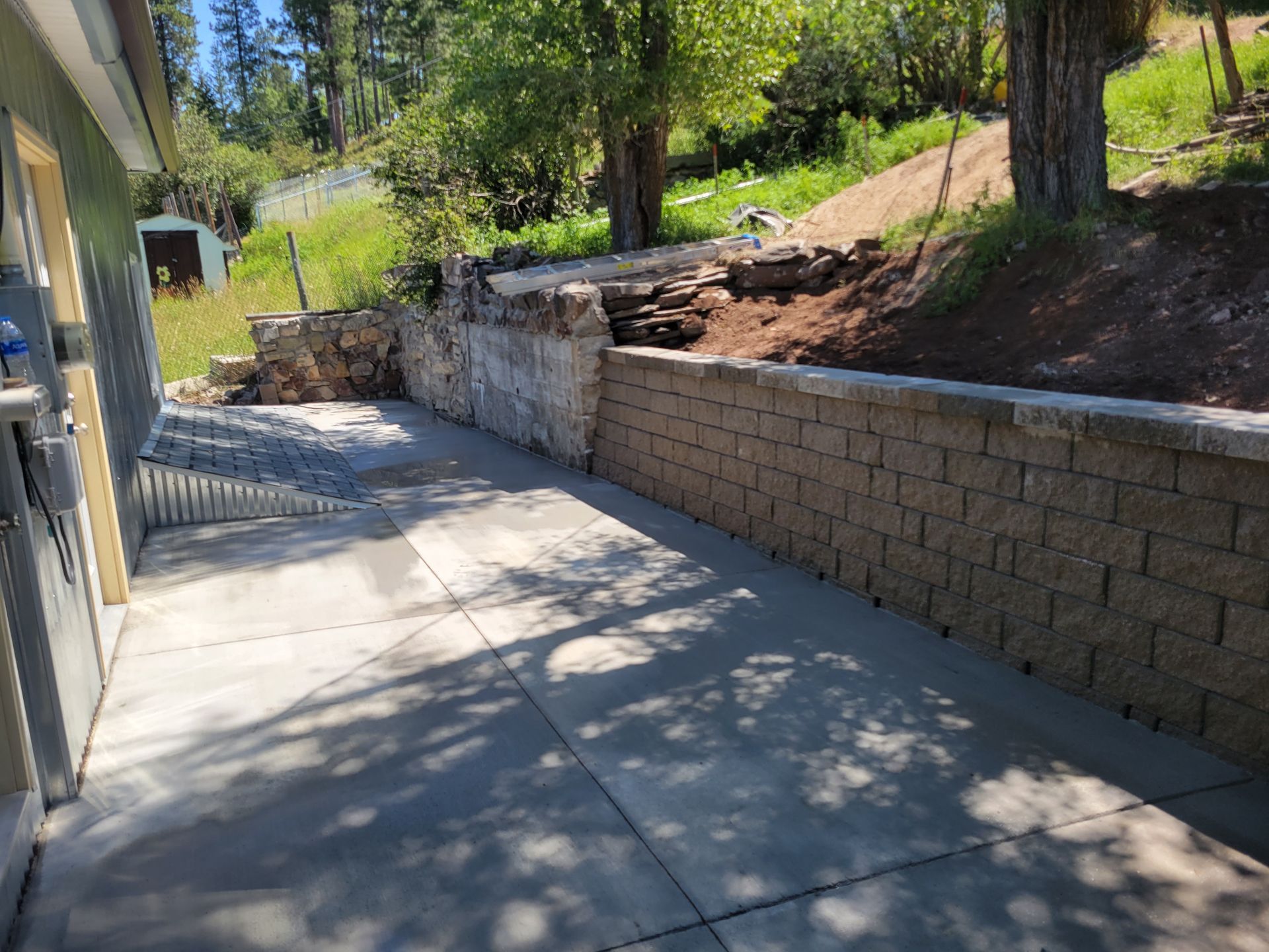 Concrete patio with a retaining wall on a hillside.