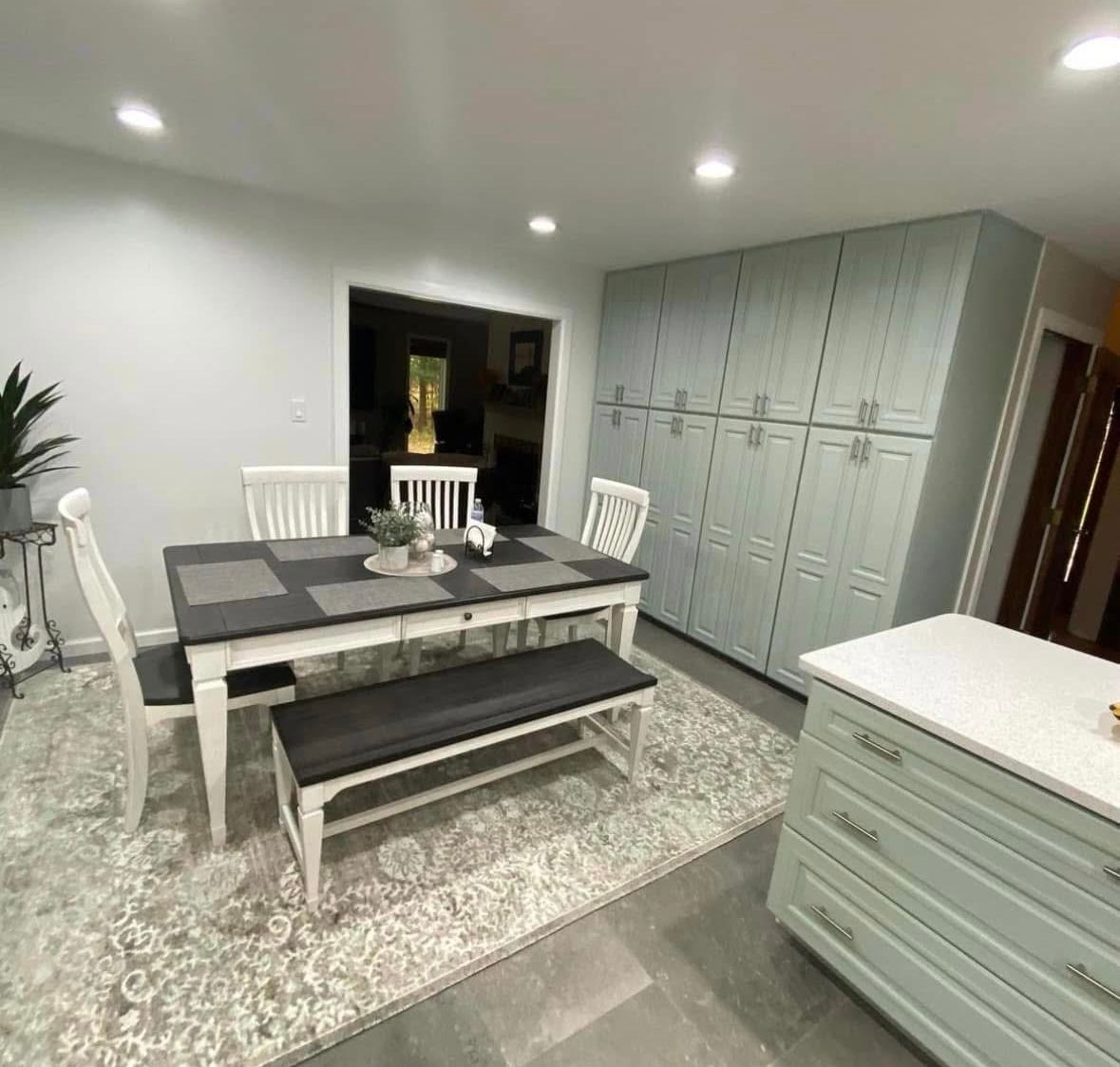 Modern dining room with gray table, bench seating, white chairs, and built-in cabinets