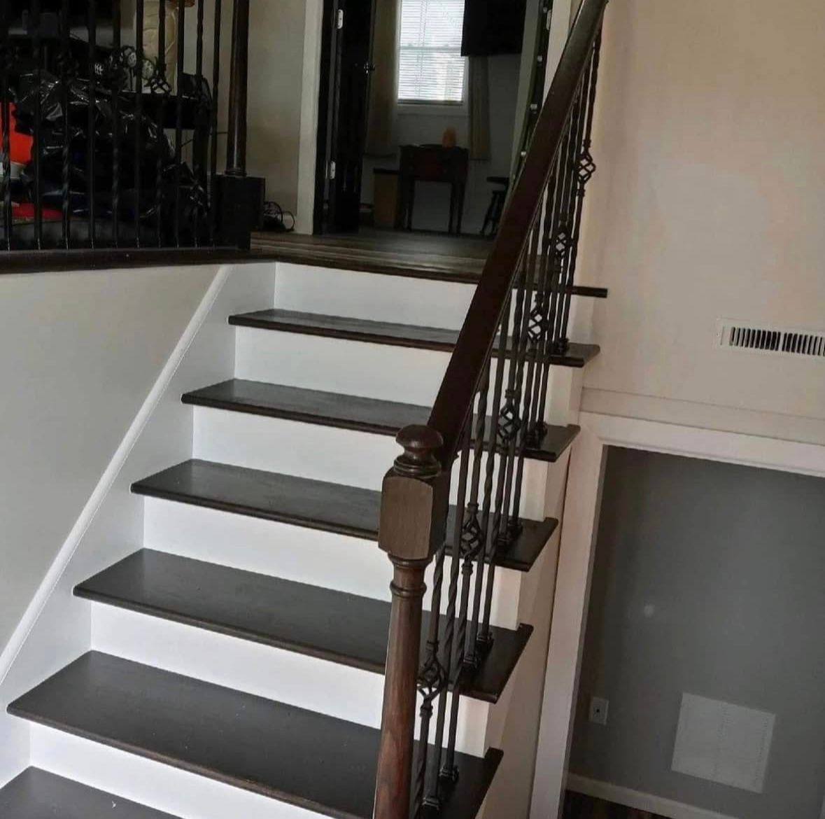Staircase with white steps, dark wooden railing, and a hallway landing in a home