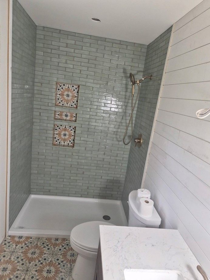 Small bathroom with tiled shower, white tub, and sink in the foreground