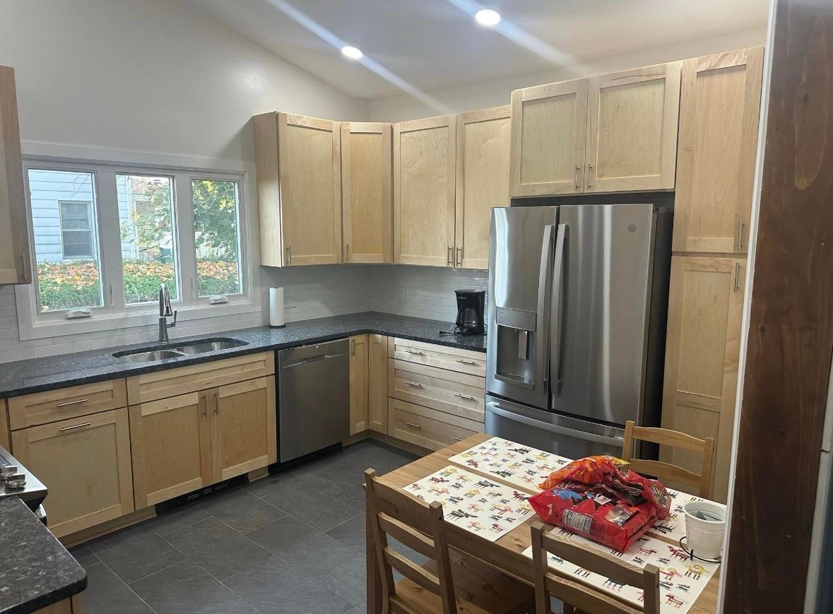 Bright kitchen with light wood cabinets, stainless steel appliances, and a small table by the window.