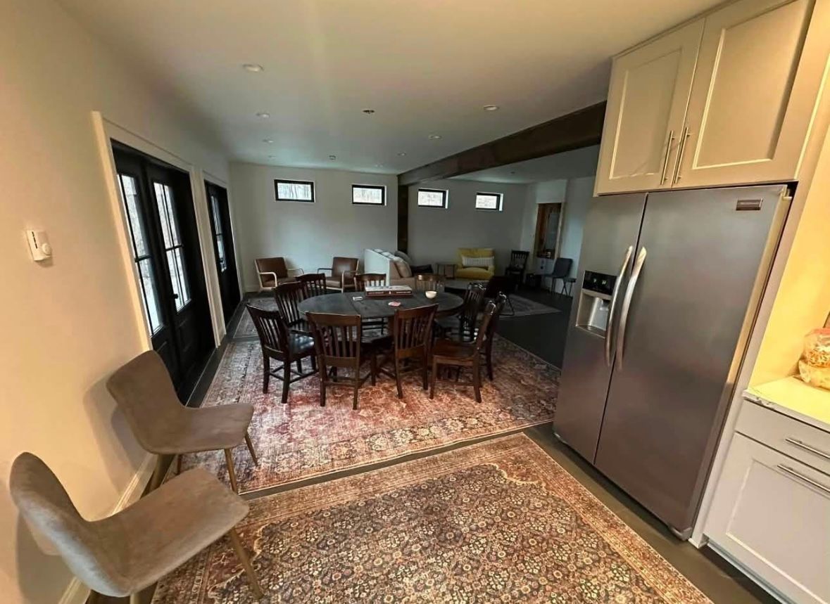 Open-plan dining and kitchen area with table, chairs, gray sofa, and stainless steel fridge
