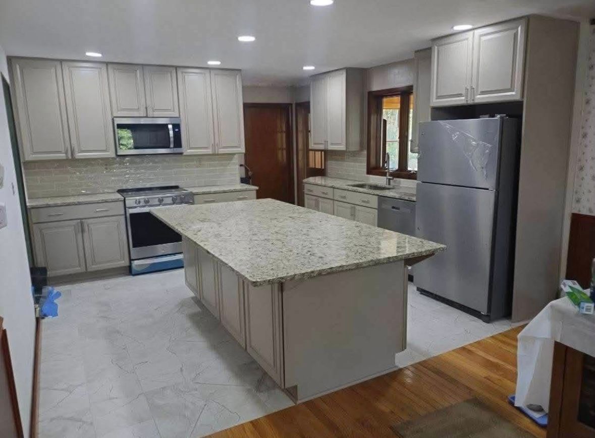 Modern kitchen with beige cabinets, granite island, stainless steel appliances, and hardwood floors
