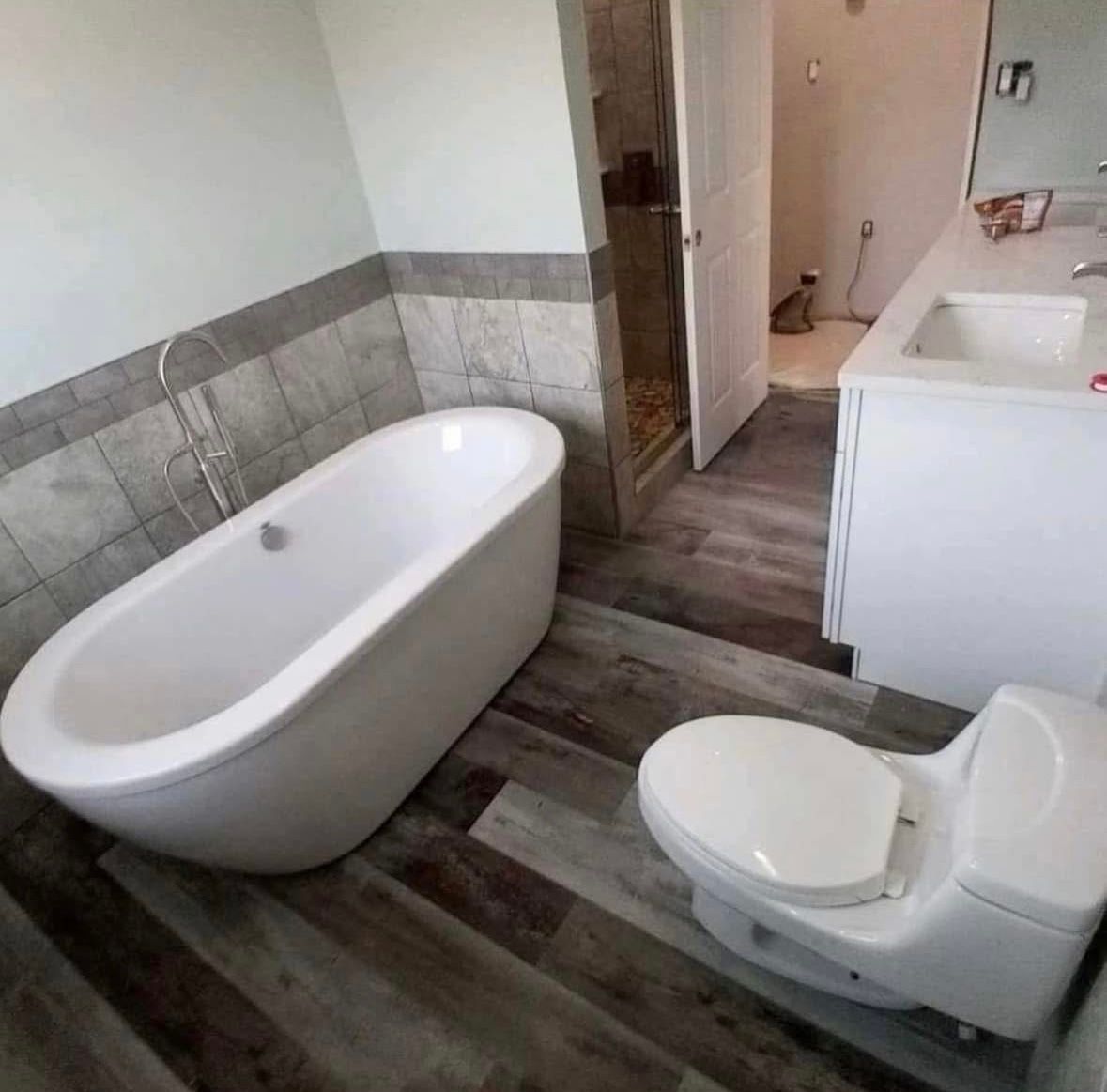 Small bathroom with a freestanding tub, toilet, and vanity in gray and white tones