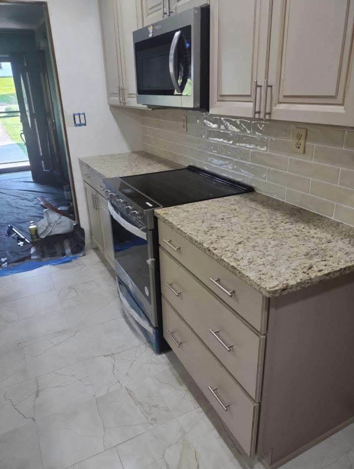Modern kitchen with beige cabinets, granite countertop, stainless stove, and microwave.