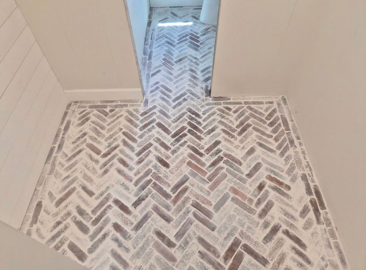 Patterned tile floor with a narrow raised strip in the center, viewed indoors.