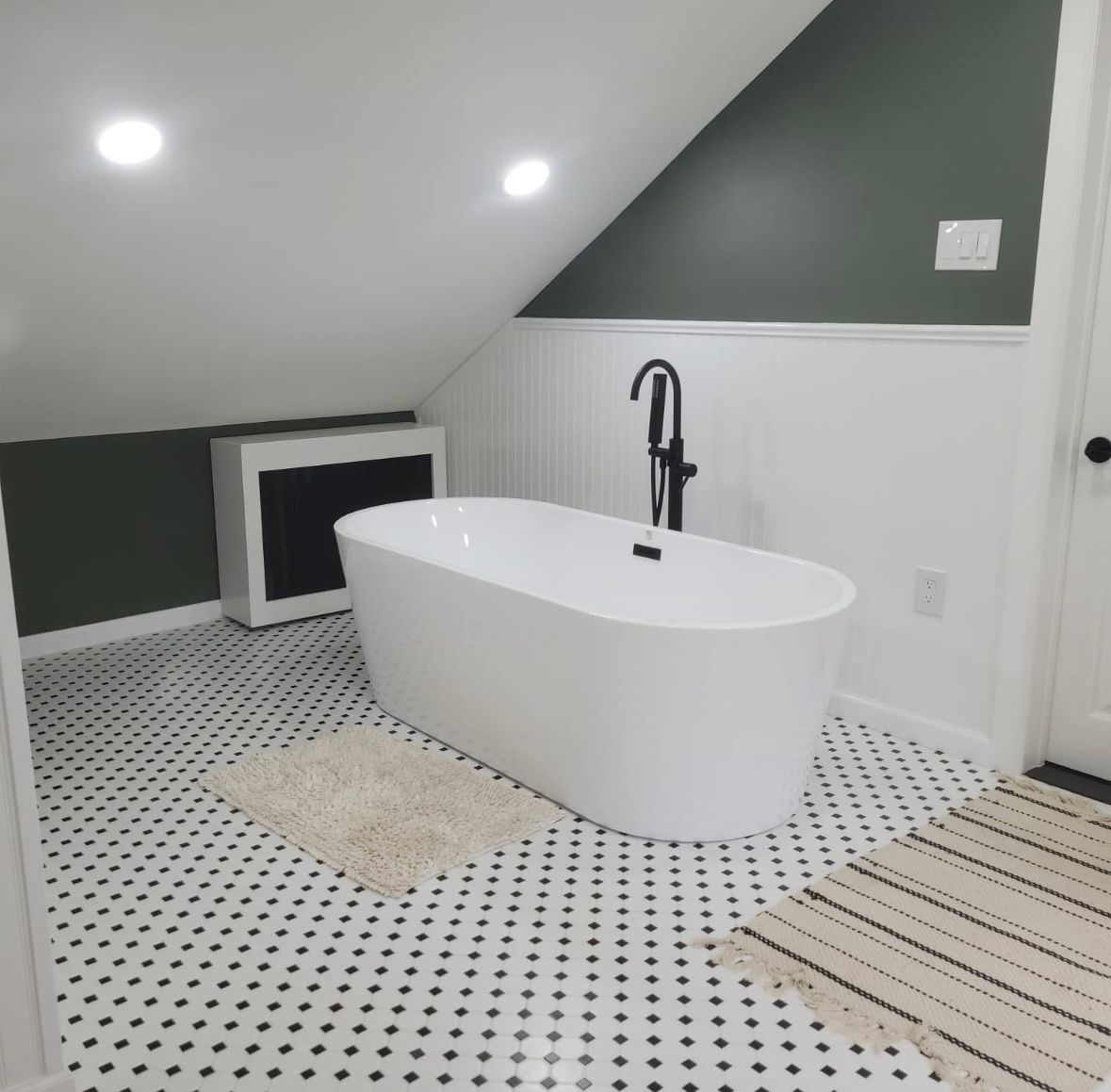 Bright attic bathroom with freestanding tub, black-and-white tile floor, and green walls