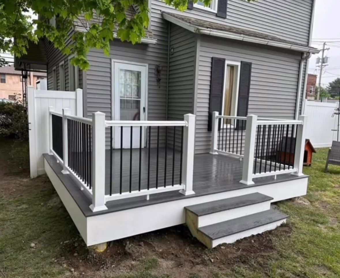 Small gray house porch with black railings, white trim, and steps leading up from the lawn