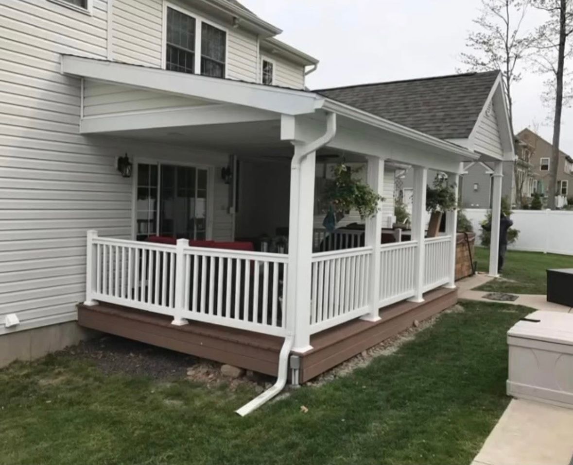 White porch with ramp and railing attached to a gray house in a suburban yard
