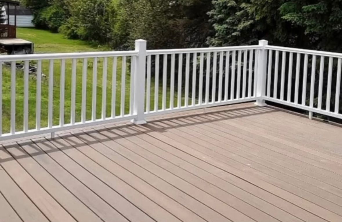 Wooden deck with white railings overlooking a grassy yard and trees