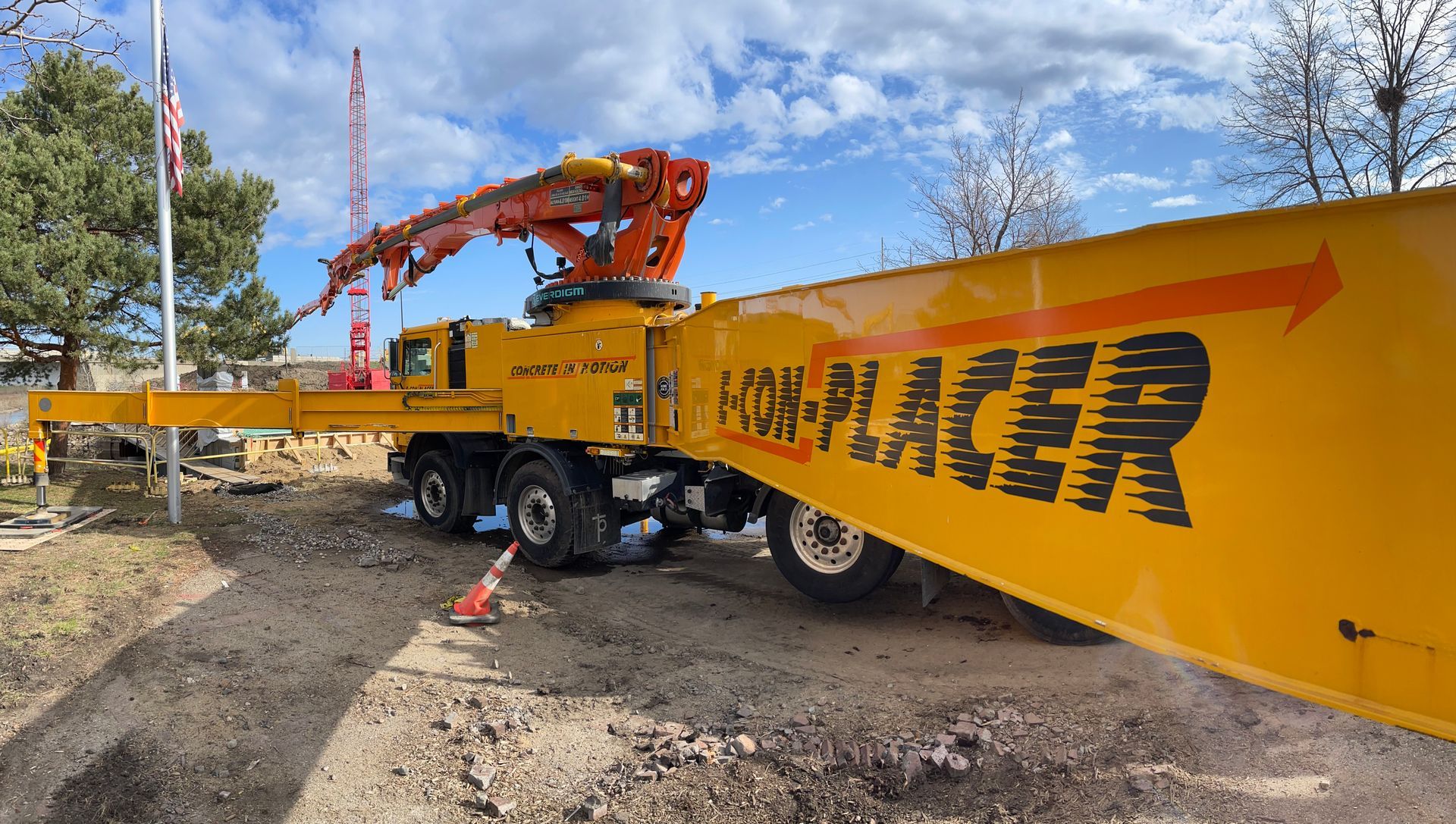 A yellow truck with a crane attached to it is parked on a dirt road.