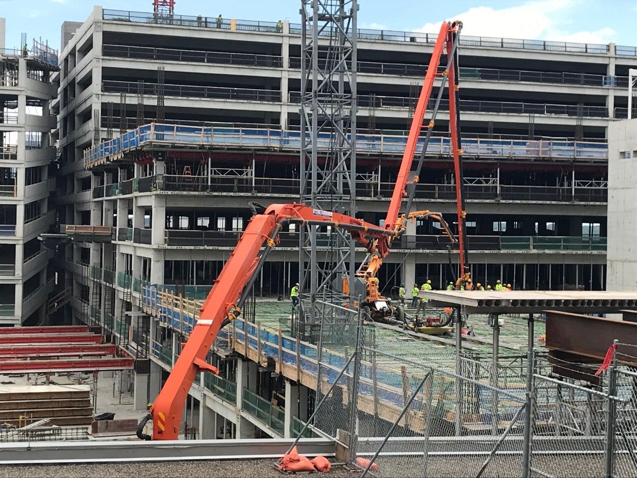 A large building under construction with a concrete pump in the foreground.