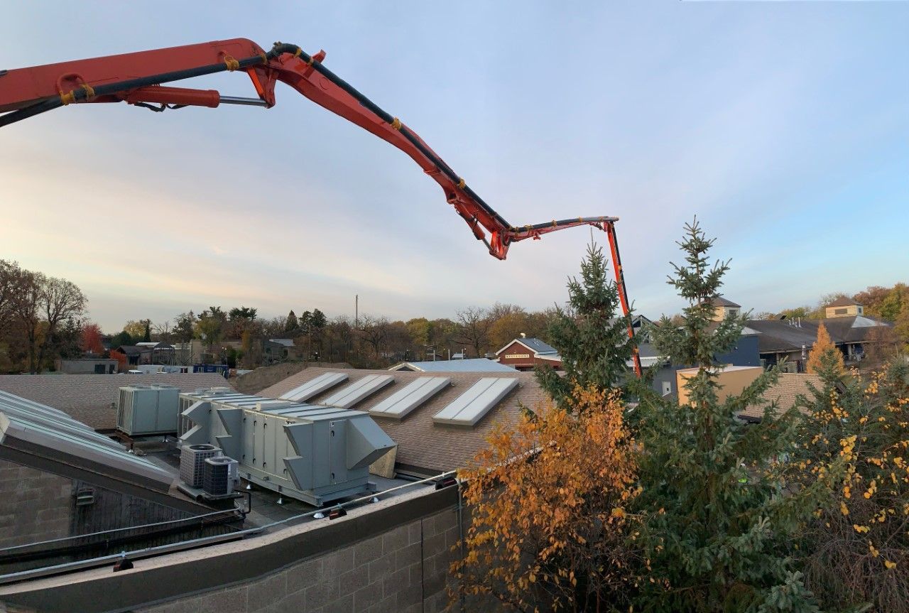 A concrete pump is being used to pour concrete on the roof of a building.
