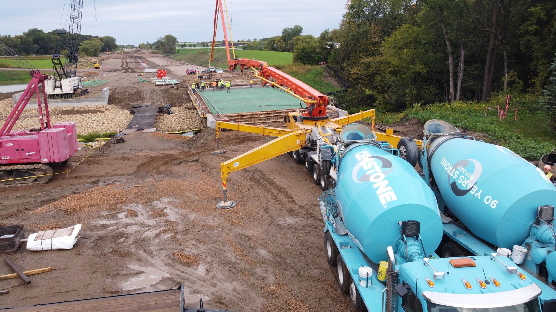 A concrete mixer truck is parked on the side of a dirt road.