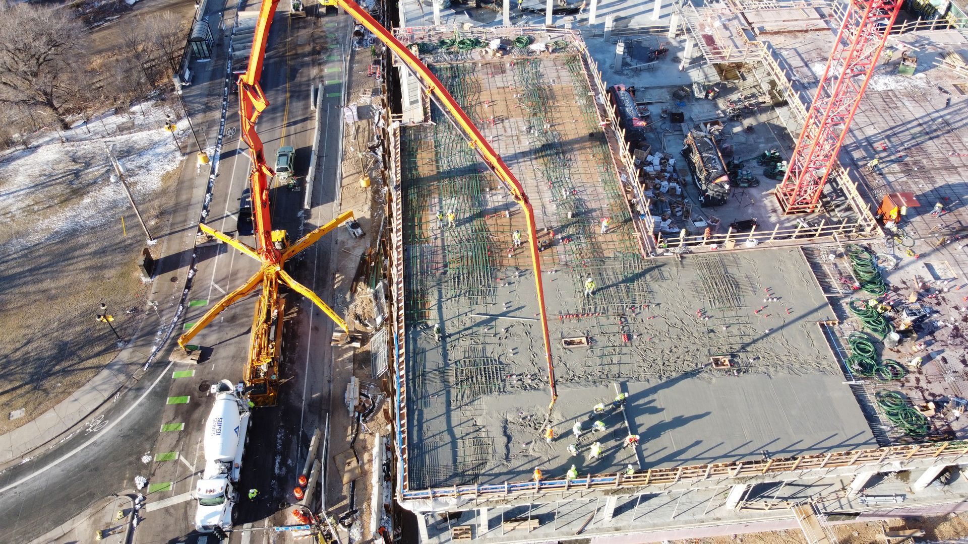 An aerial view of a construction site with a crane pumping concrete.
