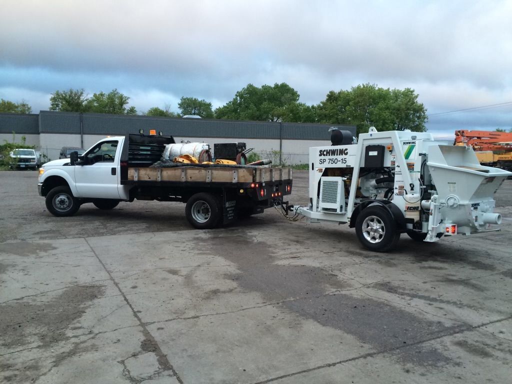 A truck is pulling a trailer with a machine attached to it