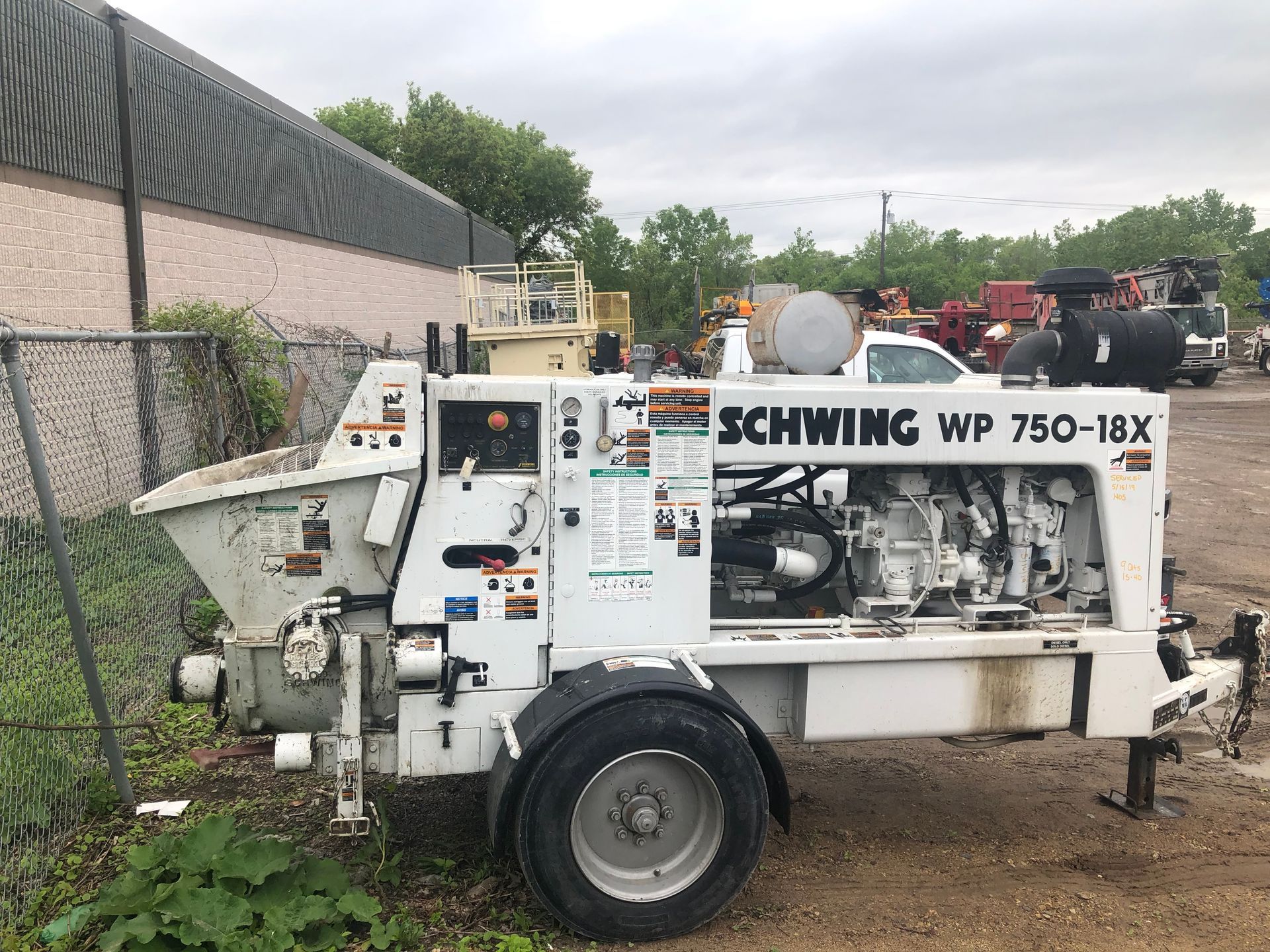 A concrete pump is parked in a parking lot next to a building.