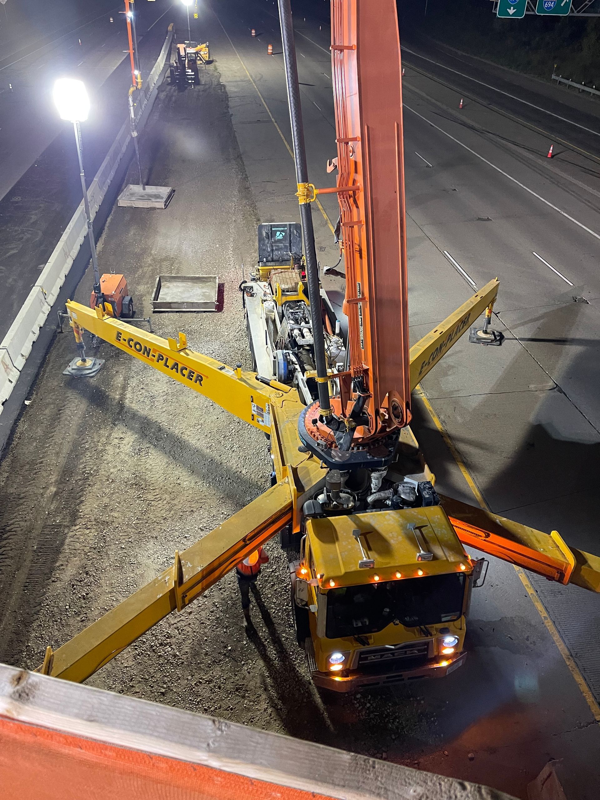 An aerial view of a concrete pump truck on a highway at night.
