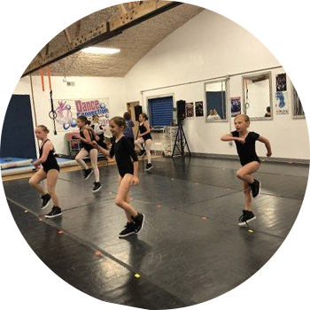 Pediatric Care, Chicago, IL Dancers in black leotards practice choreography in a studio with mirrors and a Dance Connection banner in the background.