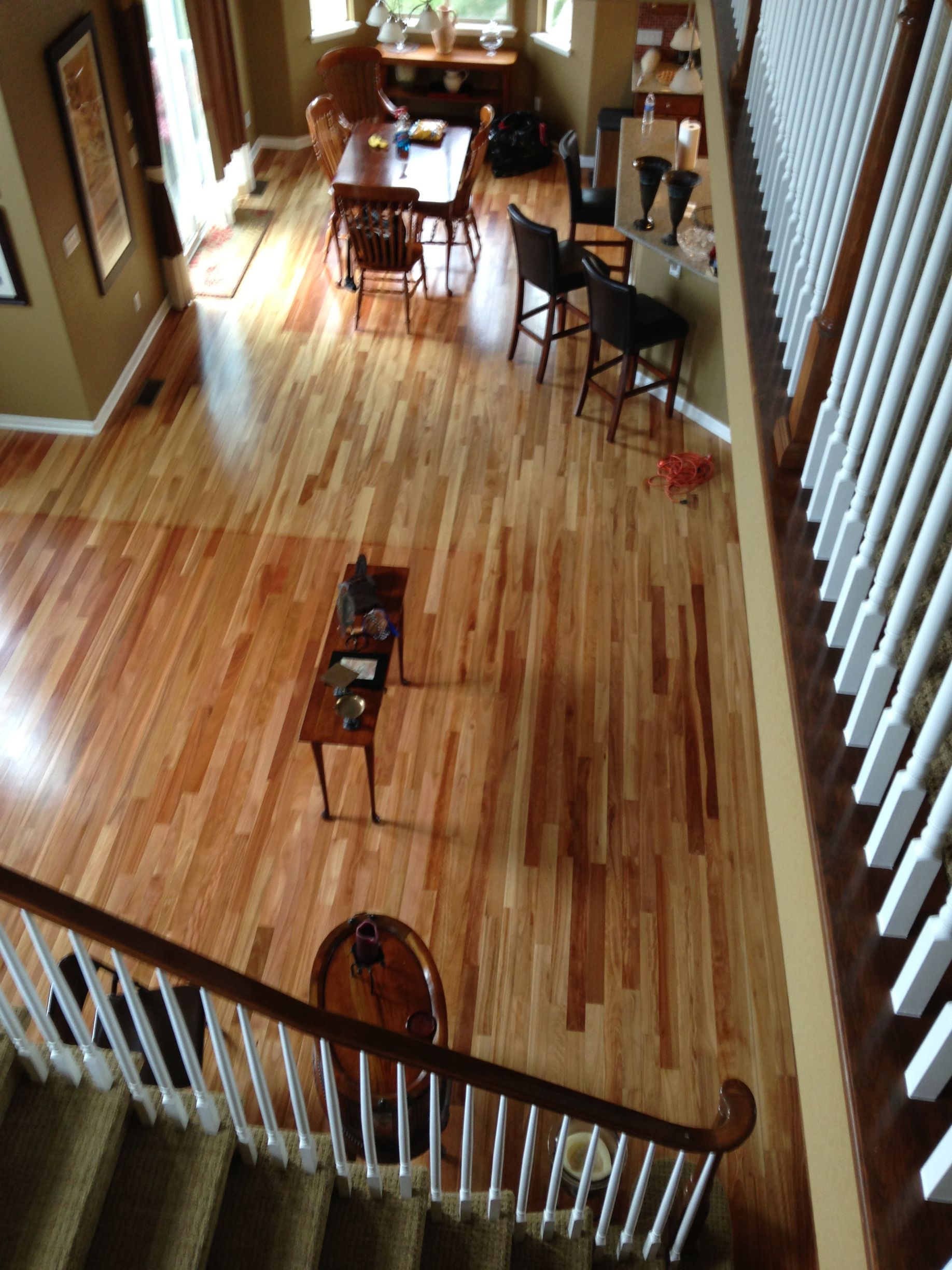 Overhead view of a hardwood floor living space with dining table, bar stools, and staircase railing.