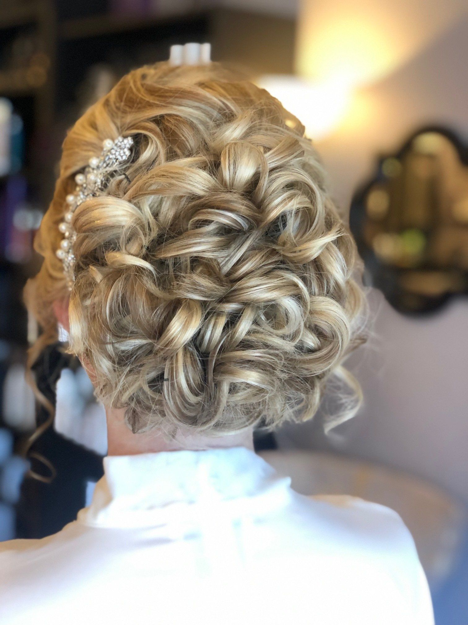 Woman with blonde, curly updo hairstyle, hair accessory.