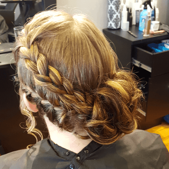 Woman with blonde and brown hair styled in a side braid and bun.