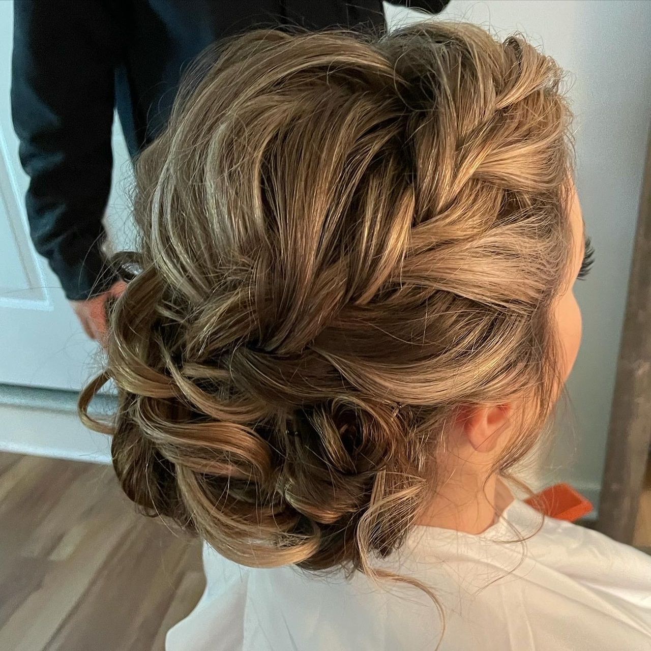 a woman is getting her hair done in a braided bun