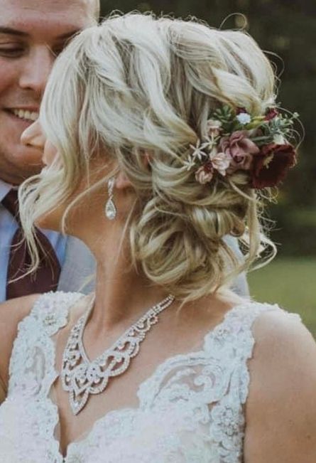 the bride is wearing a necklace and earrings and has flowers in her hair