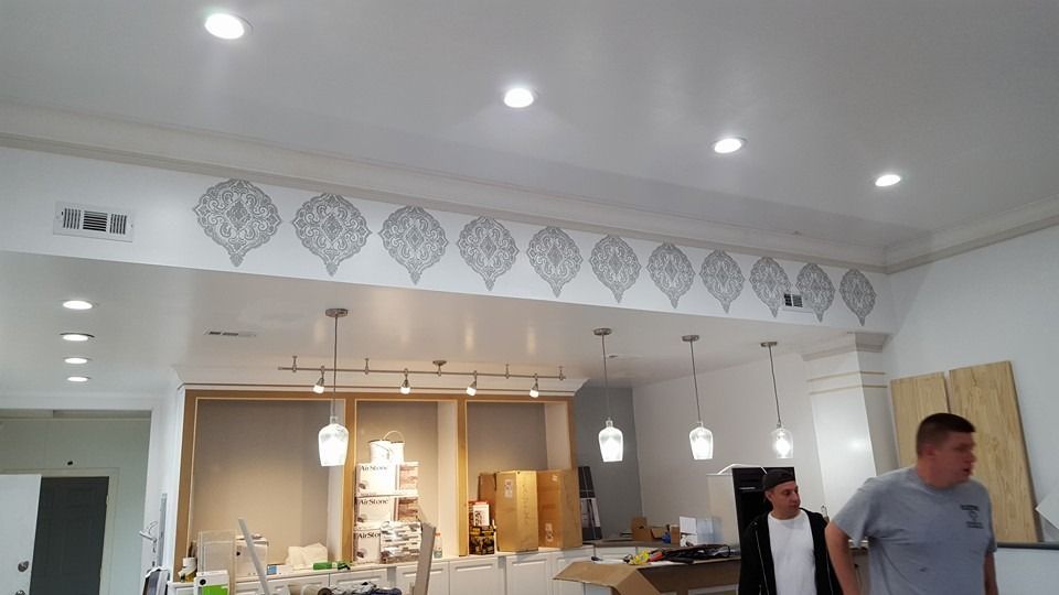 Interior view of a shop with recessed and hanging lights. Decorative patterns on wall; two men.