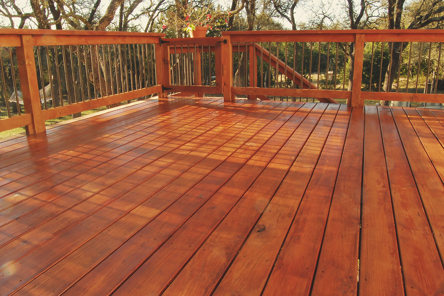 A wooden deck with a railing and trees in the background.