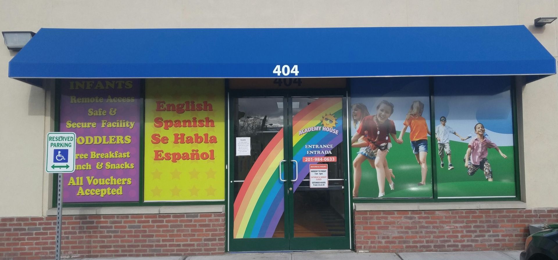 A daycare center entrance at 404 with blue awning, rainbow decal on the door, and signs offering English/Spanish services.
