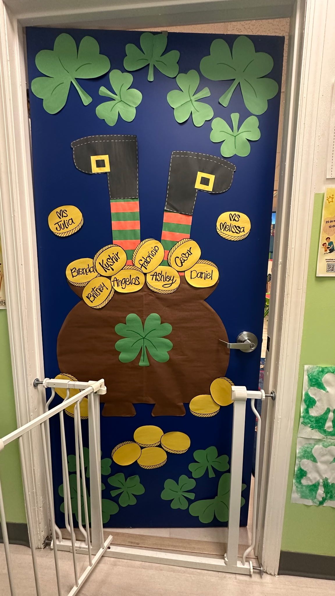 A blue door decorated for St. Patrick's Day with green shamrocks, a pot of gold, and leprechaun legs sticking out.