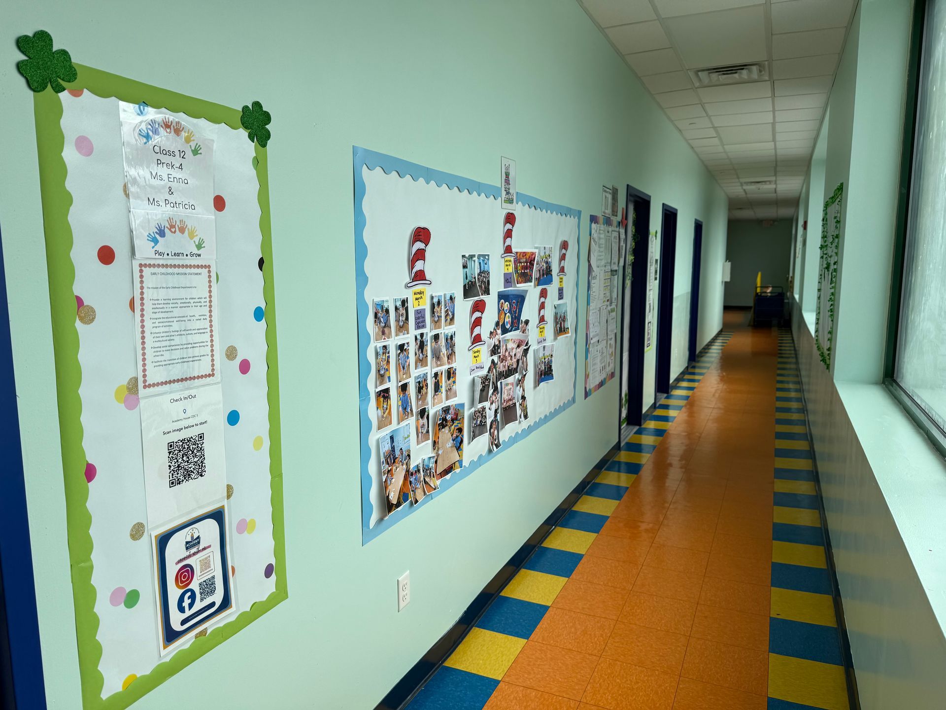 A long school hallway with light green walls, a patterned floor, and two bulletin boards decorated with educational posters.