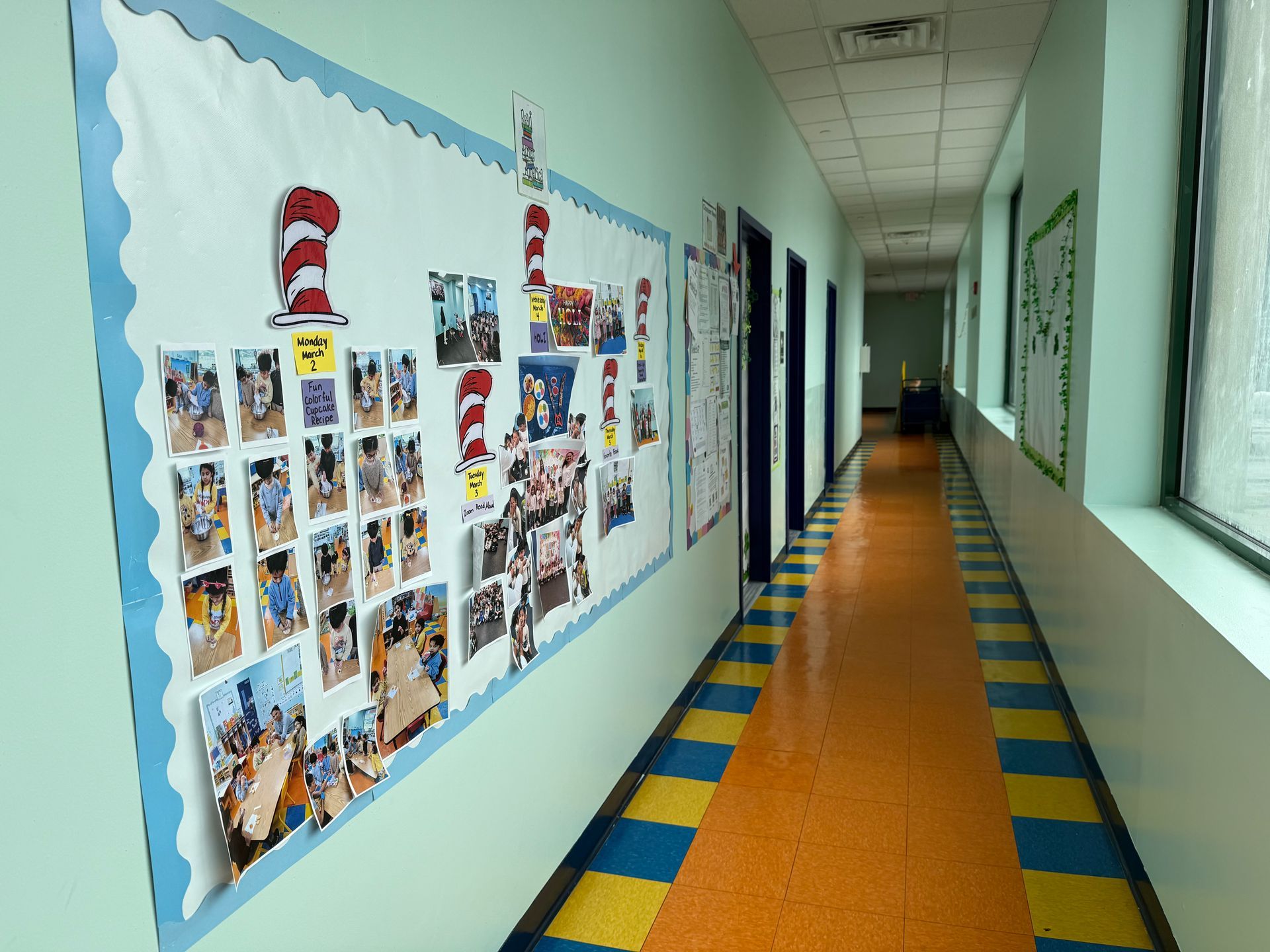 A hallway featuring a large bulletin board decorated with Dr. Seuss imagery, leading toward an open door at the end.