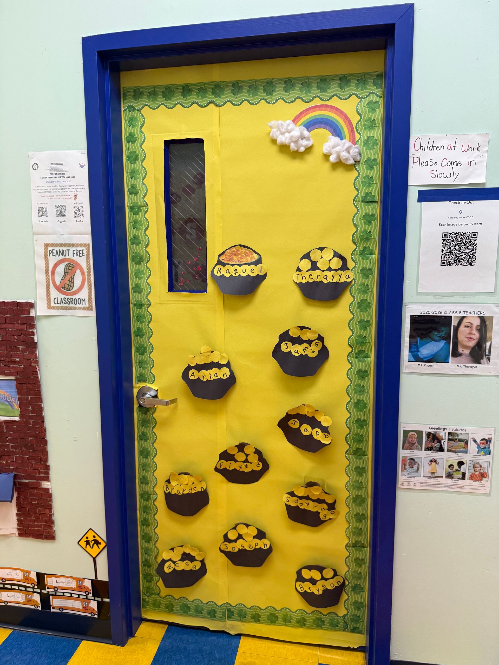 A door decorated for St. Patrick's Day with a yellow background, a rainbow, and several paper cutouts of pots of gold.