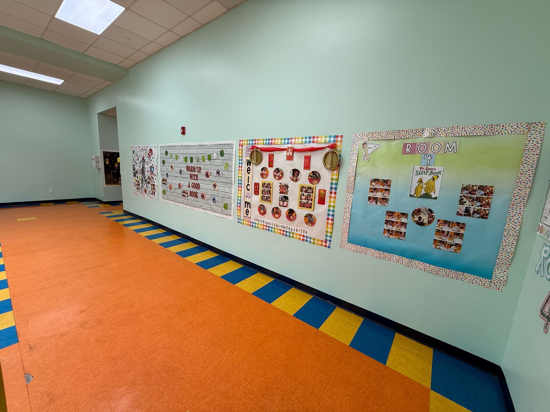 A brightly lit school hallway with colorful checkered flooring and multiple bulletin boards decorated with student work.
